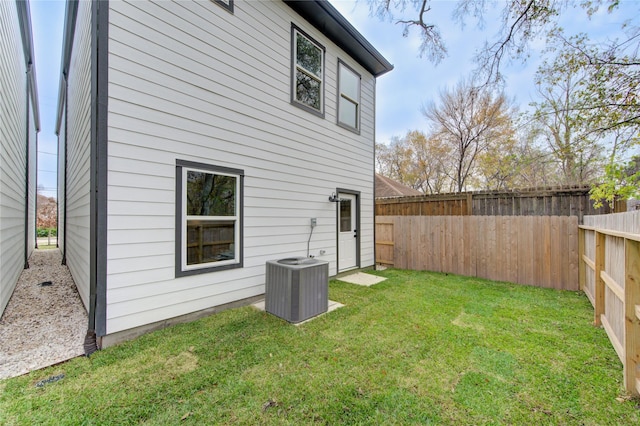 back of property with central AC unit and a lawn