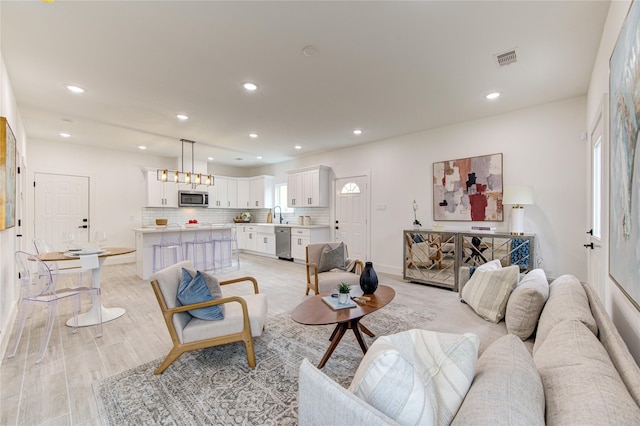 living room featuring light hardwood / wood-style flooring, a chandelier, and sink