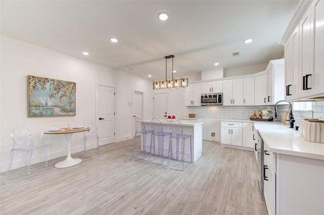 kitchen featuring a center island, sink, white cabinetry, and hanging light fixtures