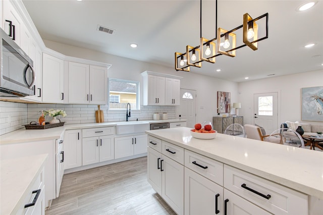 kitchen with white cabinetry, sink, tasteful backsplash, pendant lighting, and light hardwood / wood-style floors