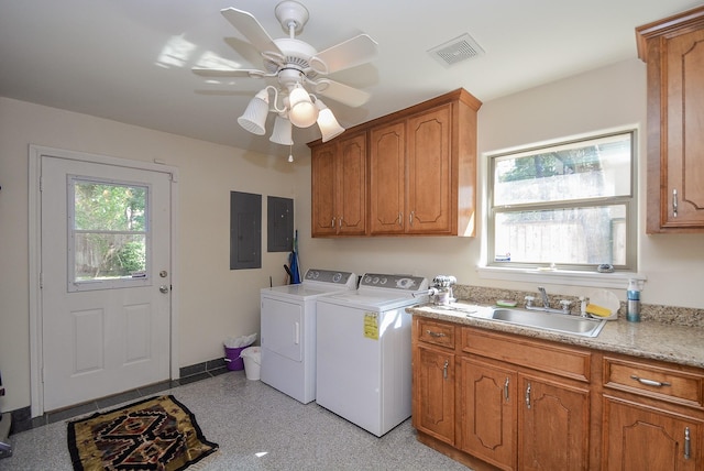 clothes washing area featuring cabinets, electric panel, sink, ceiling fan, and washing machine and dryer