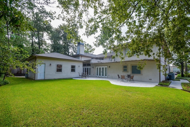 rear view of house with a lawn, a patio area, central AC, and french doors