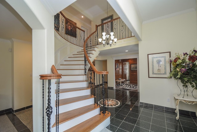 foyer with a towering ceiling, crown molding, and an inviting chandelier