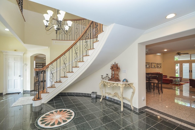 stairs featuring a towering ceiling, ceiling fan with notable chandelier, and ornamental molding