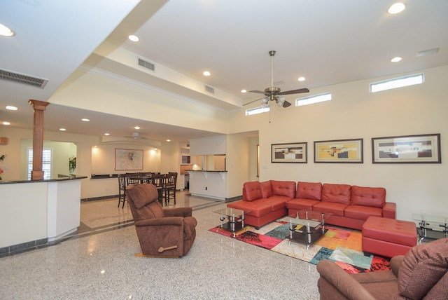 living room featuring ceiling fan, a high ceiling, and decorative columns