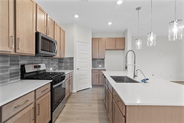 kitchen with light countertops, appliances with stainless steel finishes, a sink, and light wood-type flooring