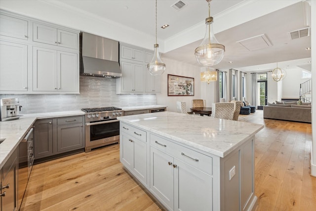 kitchen featuring gray cabinetry, oven, wall chimney range hood, tasteful backsplash, and a kitchen island