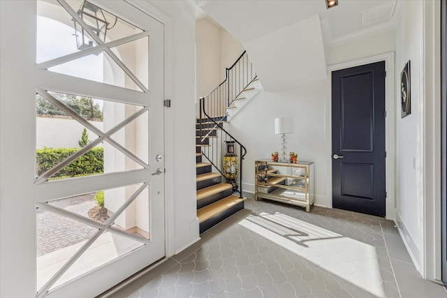 entryway with tile patterned flooring and ornamental molding