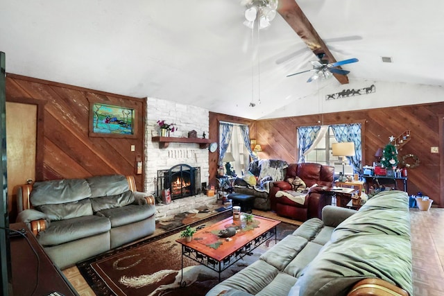 living room featuring a large fireplace, wooden walls, visible vents, ceiling fan, and vaulted ceiling with beams