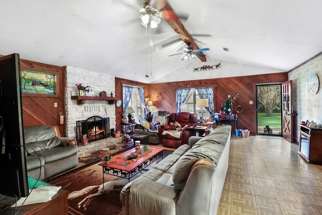 living area featuring plenty of natural light, wooden walls, beam ceiling, and a stone fireplace