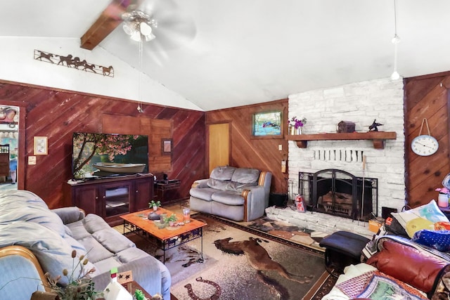 living area with vaulted ceiling with beams, wood walls, a fireplace, and a ceiling fan