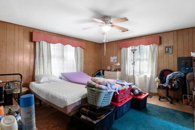 bedroom with ceiling fan, wood walls, and visible vents