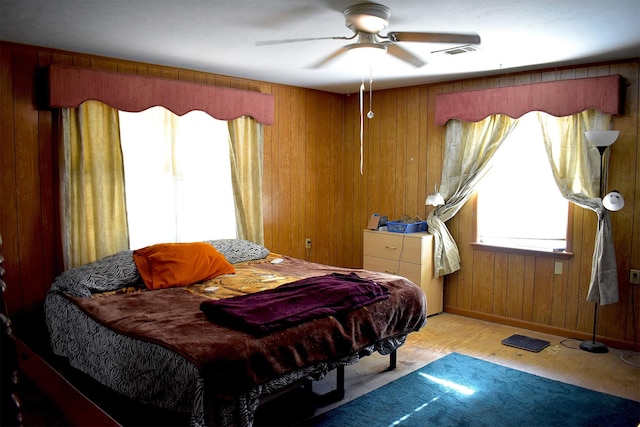 bedroom featuring wood walls, ceiling fan, visible vents, and baseboards