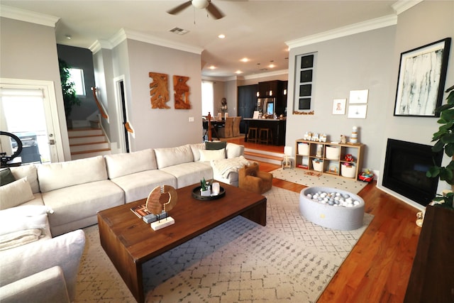 living room with dark hardwood / wood-style flooring, ceiling fan, and crown molding