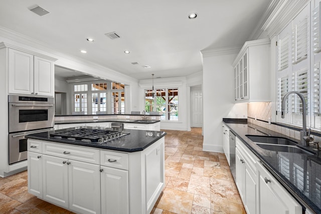 kitchen featuring white cabinets, crown molding, sink, appliances with stainless steel finishes, and tasteful backsplash