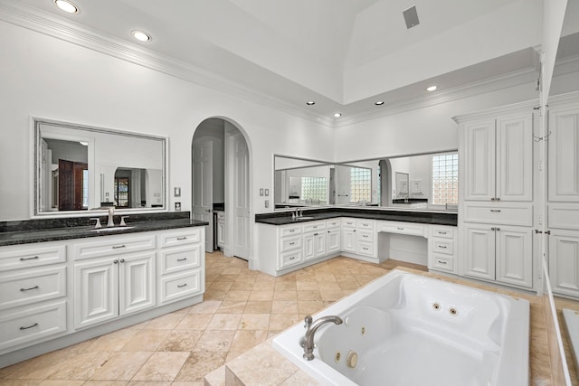 bathroom with vanity, a towering ceiling, and tiled tub