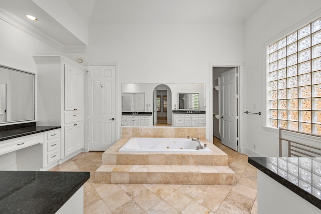 bathroom featuring vanity, a relaxing tiled tub, and a wealth of natural light