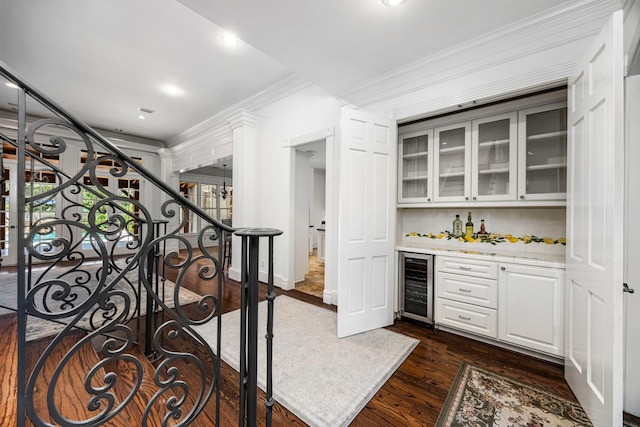 bar featuring white cabinetry, wine cooler, dark hardwood / wood-style flooring, backsplash, and crown molding