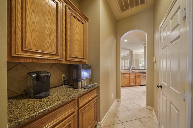 kitchen featuring sink, stainless steel dishwasher, decorative backsplash, light tile patterned floors, and stone countertops