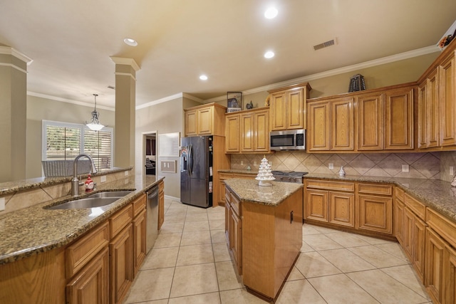 kitchen with pendant lighting, sink, ornamental molding, an island with sink, and appliances with stainless steel finishes