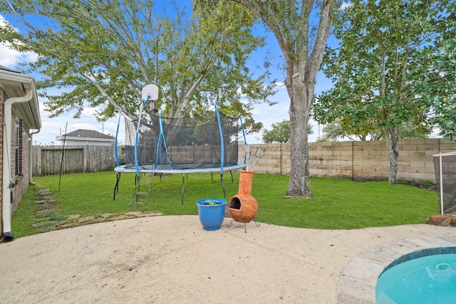 view of yard featuring a trampoline and a patio