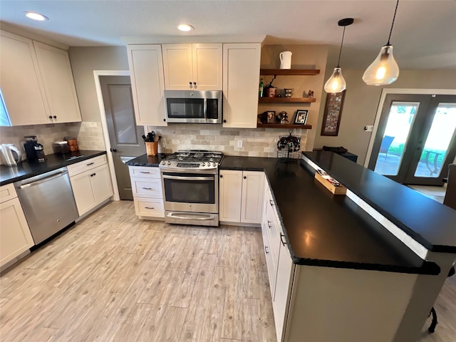 kitchen with pendant lighting, backsplash, white cabinetry, and stainless steel appliances