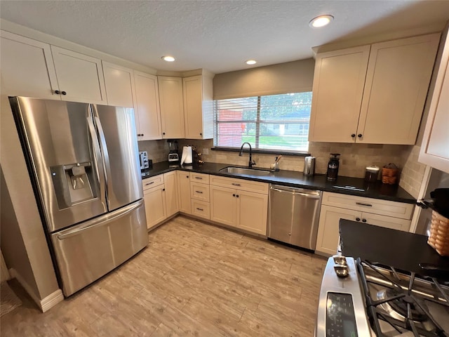 kitchen featuring backsplash, sink, stainless steel appliances, and light hardwood / wood-style flooring