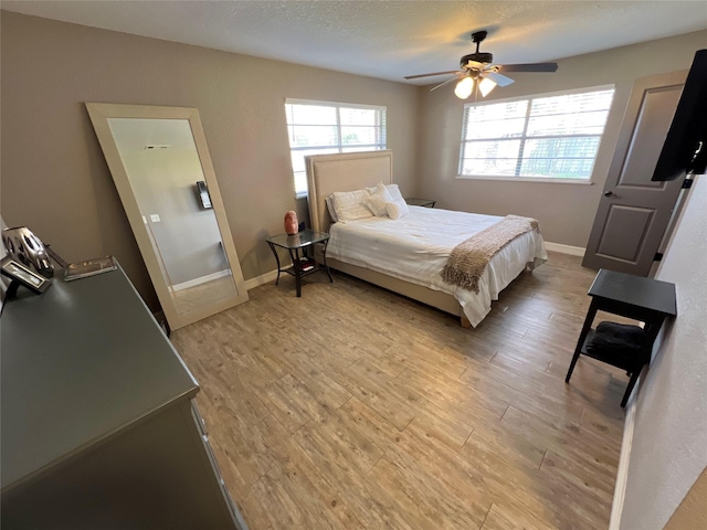 bedroom featuring ceiling fan, a textured ceiling, and light wood-type flooring