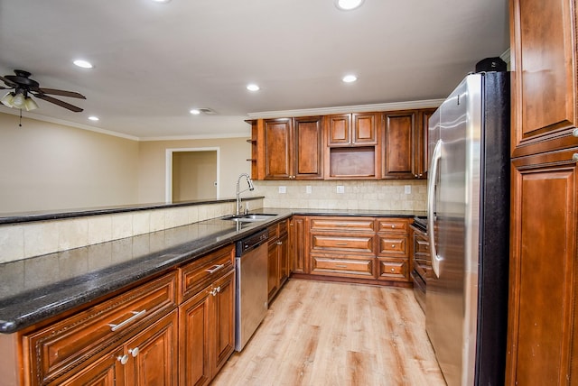 kitchen with sink, decorative backsplash, ornamental molding, stainless steel appliances, and light wood-type flooring