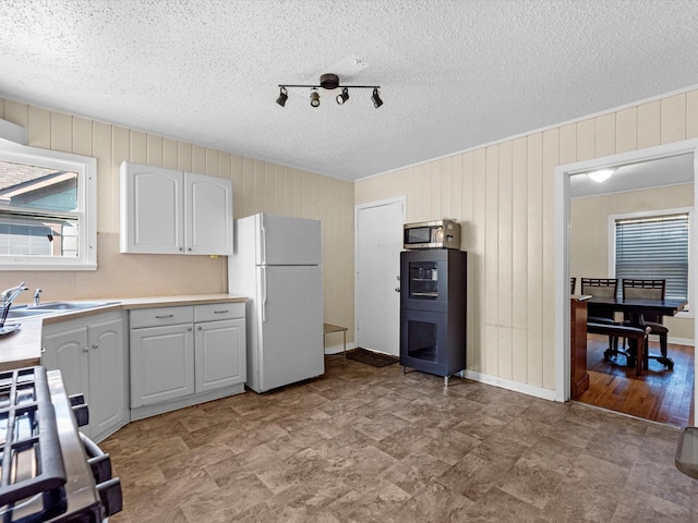 kitchen featuring white cabinetry, sink, stove, white fridge, and a textured ceiling