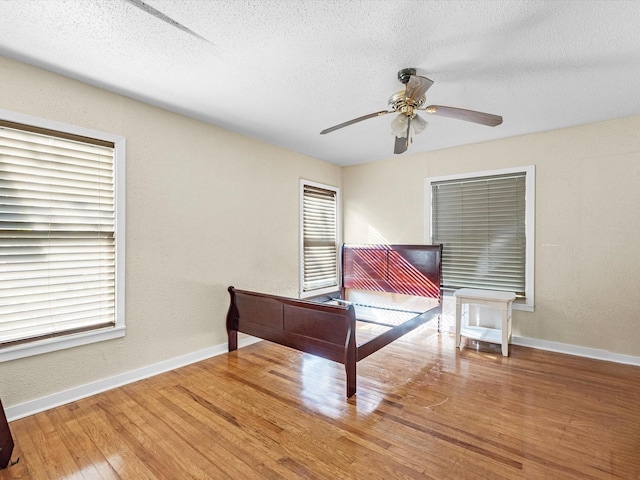 unfurnished bedroom with a textured ceiling, hardwood / wood-style flooring, and ceiling fan