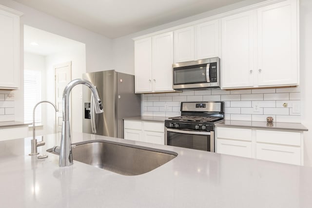 kitchen featuring white cabinets, stainless steel appliances, and tasteful backsplash