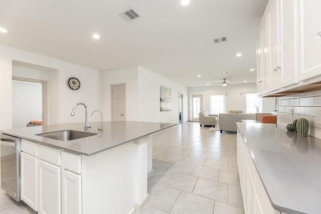 kitchen featuring dishwasher, a kitchen island with sink, sink, and white cabinets