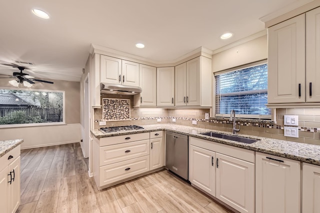 kitchen with light stone countertops, white cabinetry, sink, light hardwood / wood-style floors, and appliances with stainless steel finishes