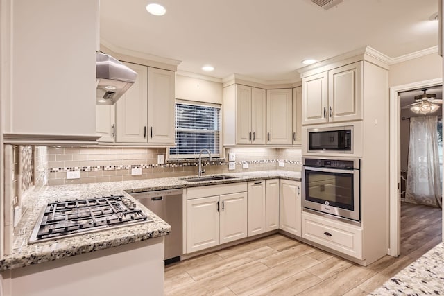 kitchen featuring decorative backsplash, light stone counters, sink, and stainless steel appliances