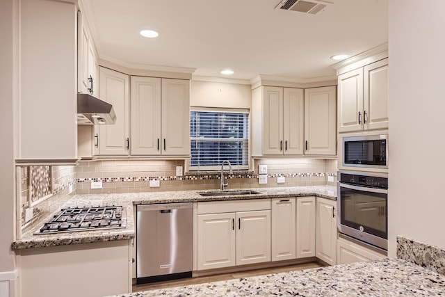 kitchen with decorative backsplash, appliances with stainless steel finishes, light stone counters, and sink