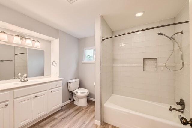 full bathroom featuring toilet, hardwood / wood-style floors, vanity, and tiled shower / bath