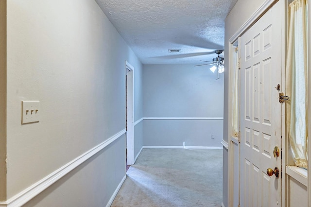 corridor with light carpet and a textured ceiling