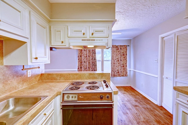 kitchen with electric stove, sink, light wood-type flooring, a textured ceiling, and white cabinetry