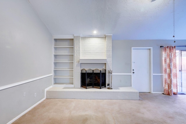 unfurnished living room with carpet, built in shelves, a textured ceiling, and a brick fireplace