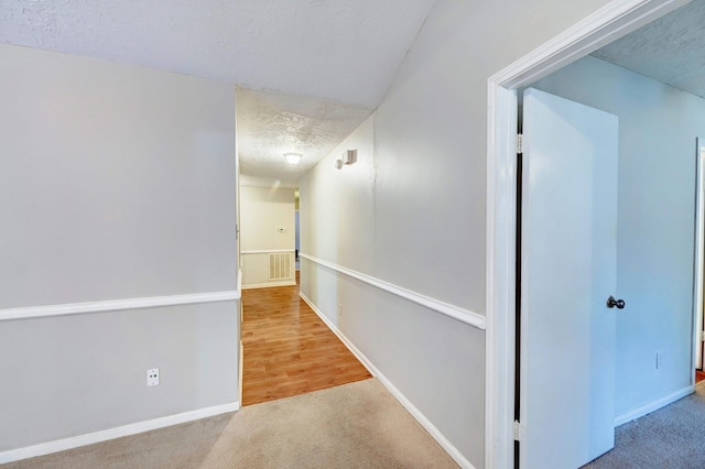 hallway featuring carpet and a textured ceiling