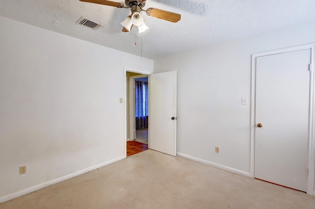 carpeted spare room with a textured ceiling and ceiling fan