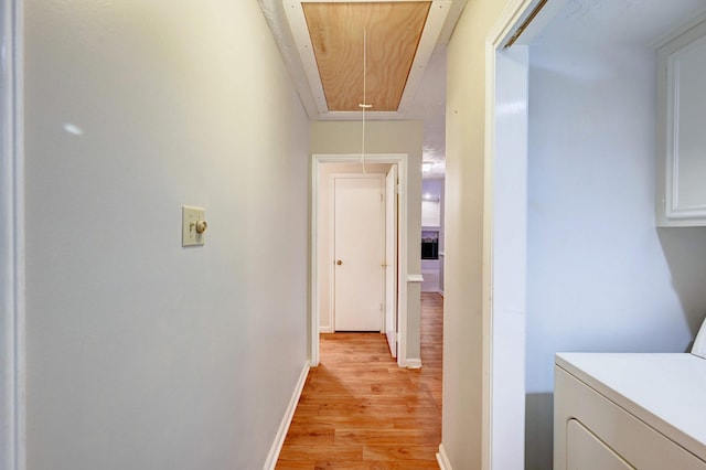 corridor featuring light wood-type flooring and washer / dryer