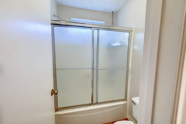 bathroom with toilet, enclosed tub / shower combo, and a textured ceiling