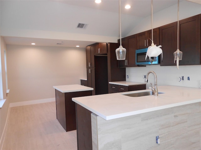 kitchen with pendant lighting, a center island, lofted ceiling, sink, and dark brown cabinetry