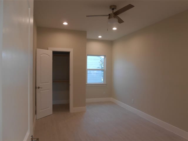 unfurnished bedroom featuring a walk in closet, a closet, ceiling fan, and light hardwood / wood-style floors