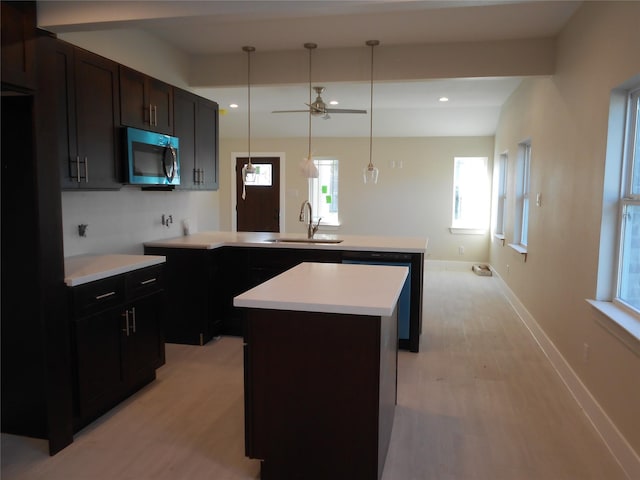 kitchen featuring ceiling fan, a center island, sink, decorative light fixtures, and dishwashing machine