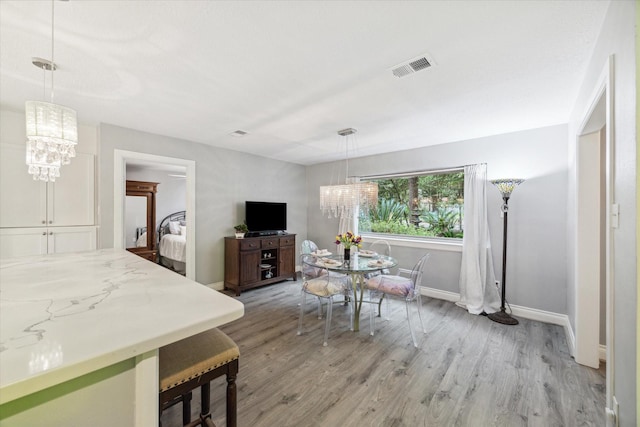 bedroom with light hardwood / wood-style floors and an inviting chandelier