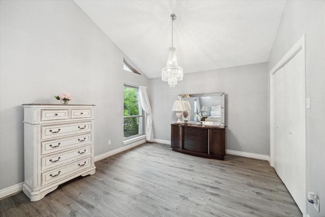 unfurnished dining area with a notable chandelier, lofted ceiling, and light hardwood / wood-style flooring