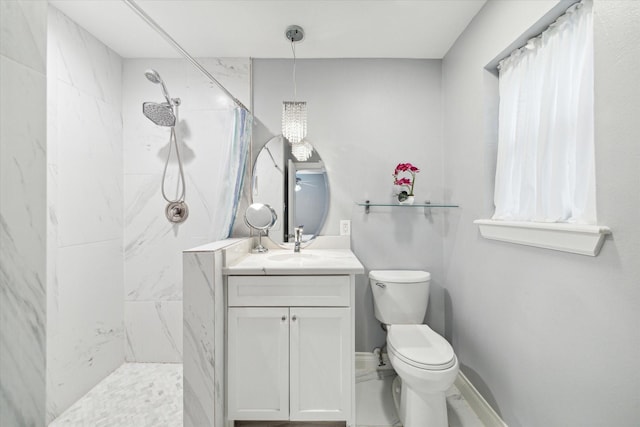 bathroom with a tile shower, vanity, and toilet